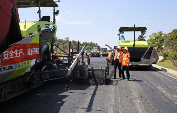 攤鋪機(jī)、壓路機(jī)等設(shè)備緊張有序運(yùn)行，高達(dá)170℃的瀝青混合料炙烤著公路人
